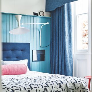 Bedroom with blue wall panelling and oversized white wall light