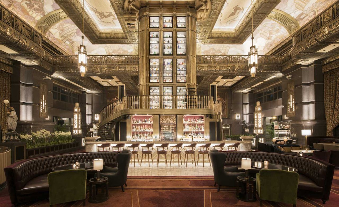 Wide shot of bar showing high ceilings &amp; gold decorative walls and stairs 