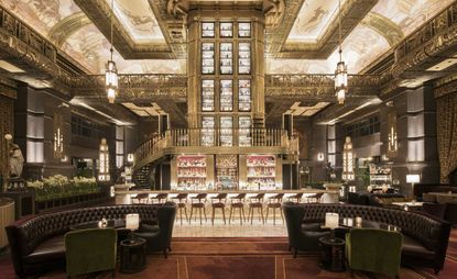 Wide shot of bar showing high ceilings & gold decorative walls and stairs 