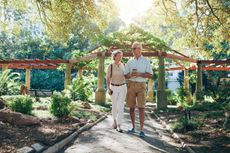 GEW03B Full length portrait of happy senior couple walking together in a city park. Mature man and woman on a vacation.