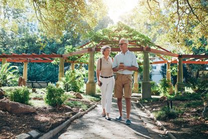 GEW03B Full length portrait of happy senior couple walking together in a city park. Mature man and woman on a vacation.