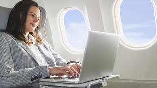 Businesswoman using laptop in business class airplane cabin