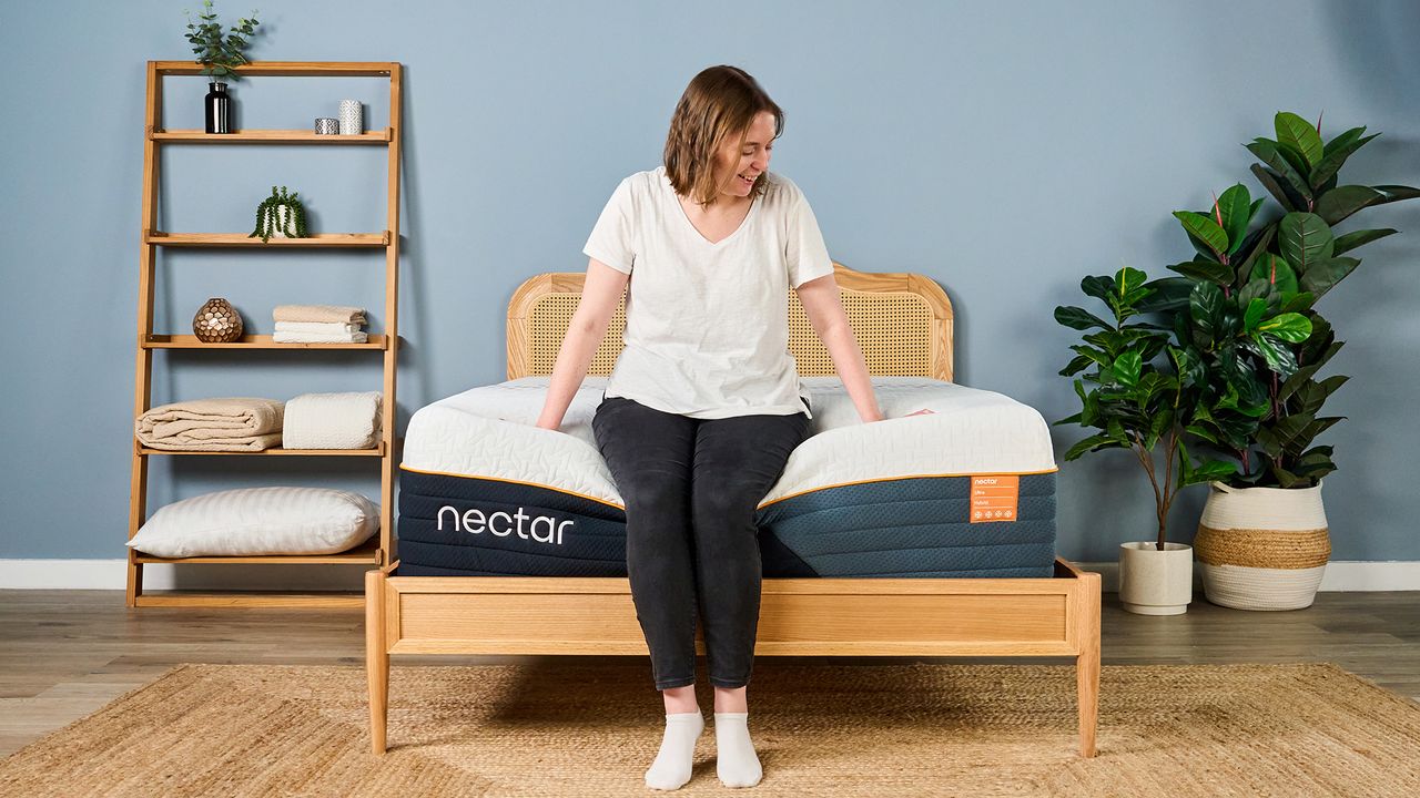 A female Tom's Guide mattress tester sitting on the end of the Nectar Ultra Hybrid mattress showing its weak edge support