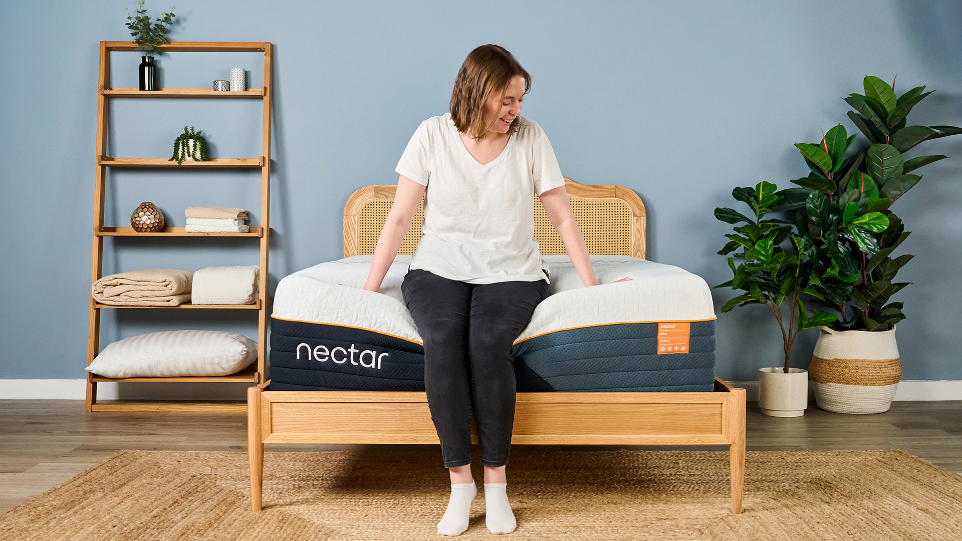 A female Tom's Guide mattress tester sitting on the end of the Nectar Ultra Hybrid mattress showing its weak edge support