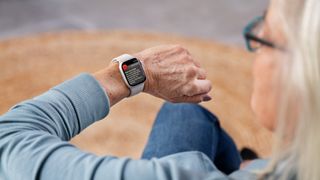 A person looks at an Apple Watch on their wrist. The device is warning them that they have a high heart rate.