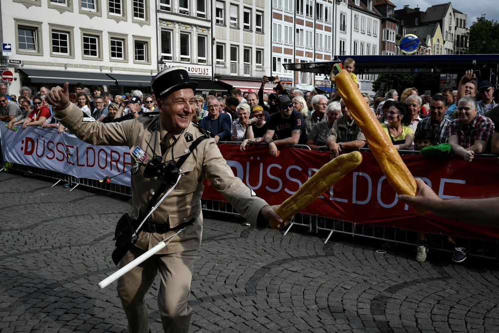 A man wearing an old French gendarme uniform fights with a fake baguette as he performs during the parade of the team presentation