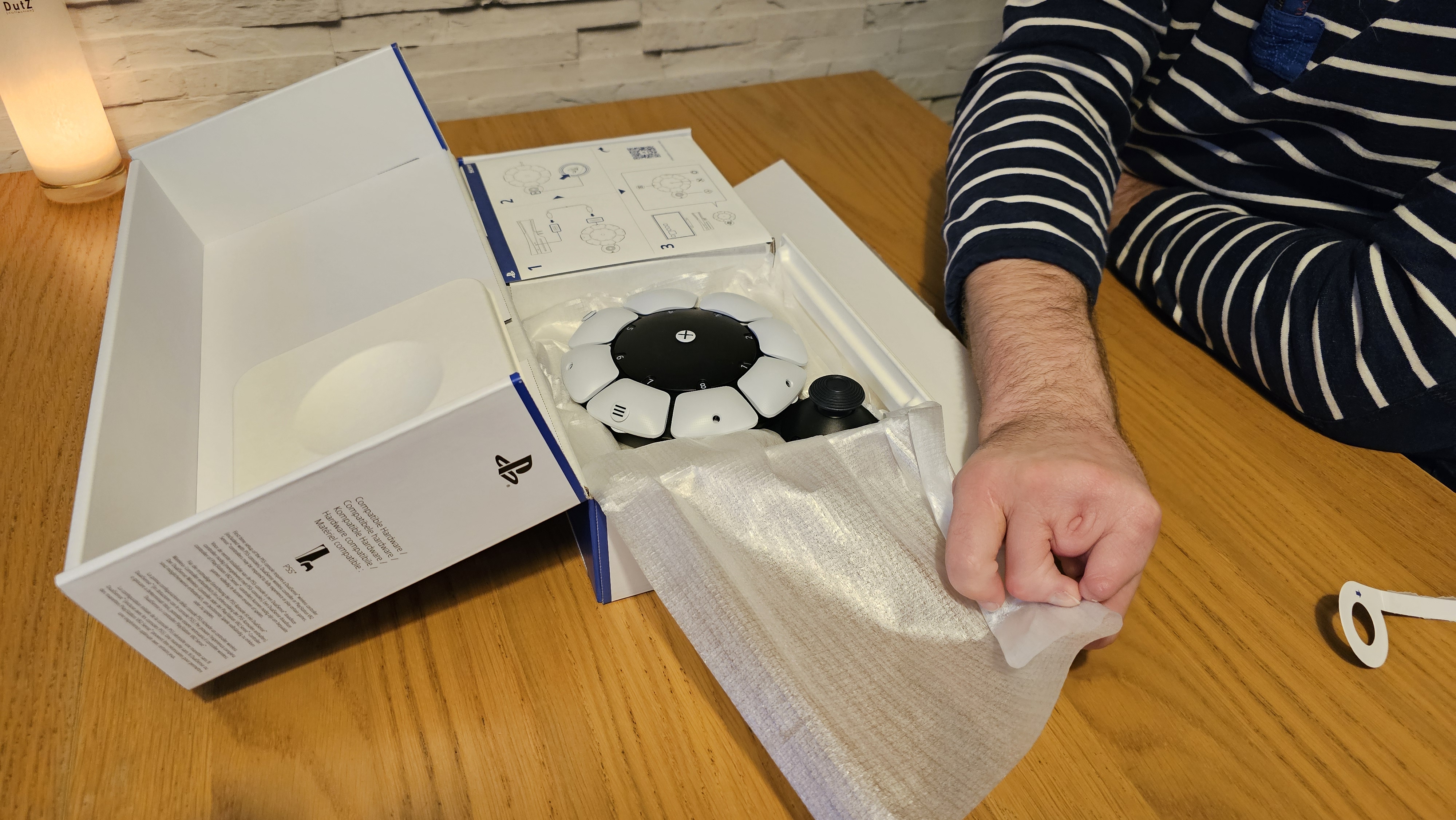 Unboxing the PlayStation Access controller with one hand on a wooden surface