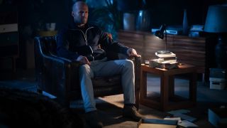 Jason Statham waits in the dark with a gun in Wrath Of Man.