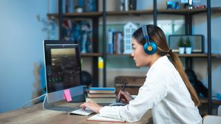 A woman sits at a desk and works on some video editing. 