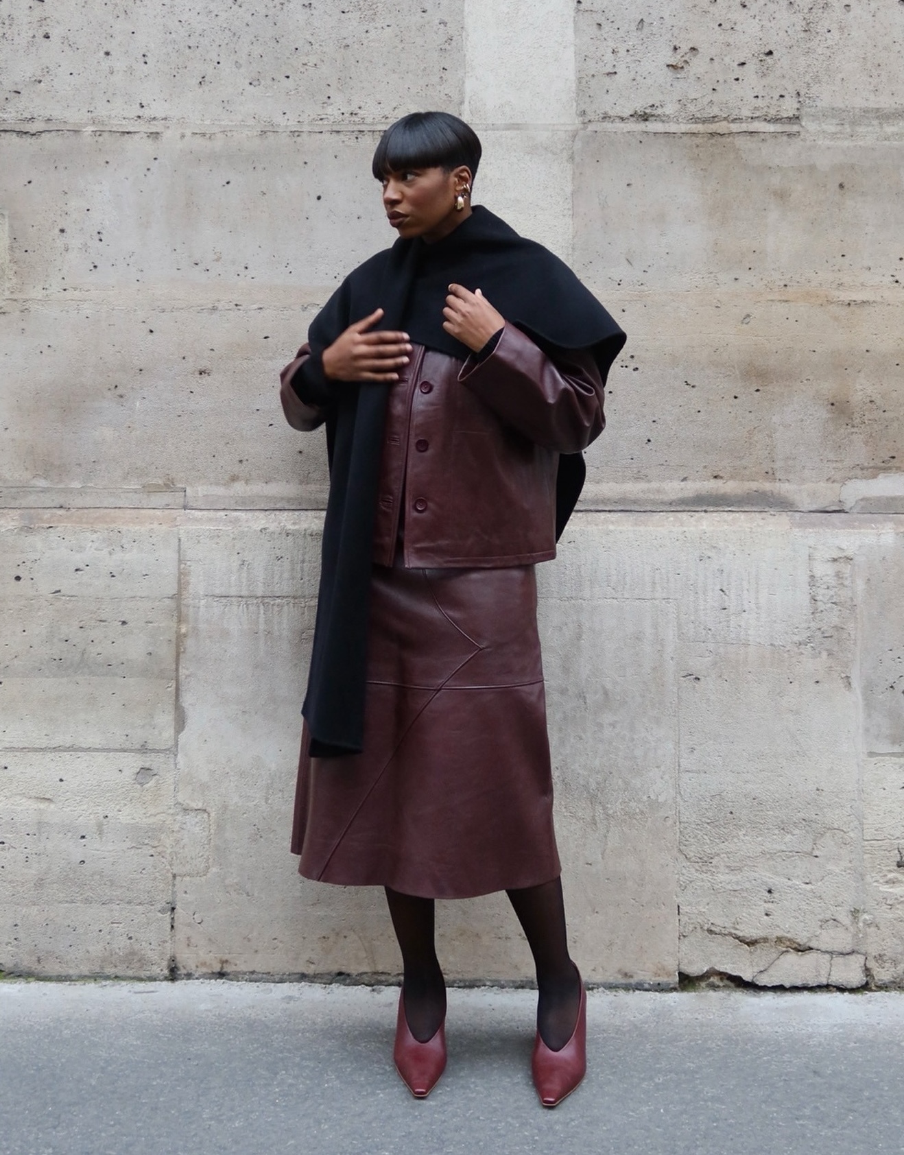 @thevisuelofgrace wearing a burgundy leather jacket and matching skirt.
