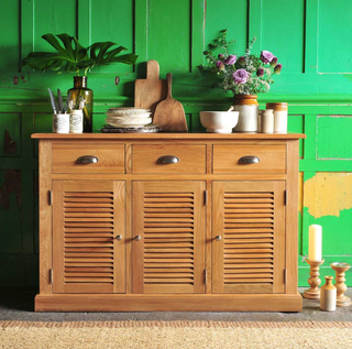 Hamilton Oak 3 Door Sideboard covered with potted plants and assorted plates and cutlery in a room with green panelled walls
