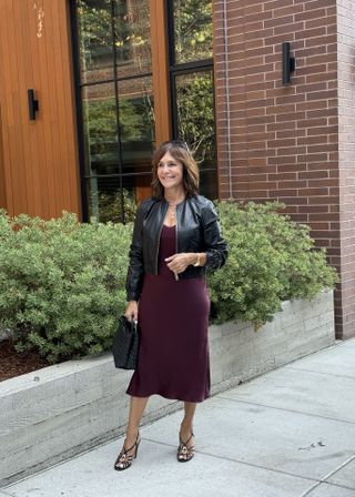 AReplica Store buyer wearing a burgundy dress and a black leather bomber jacket.