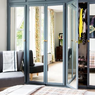 Wall of built-in mirrored wardrobes in a blue bedroom