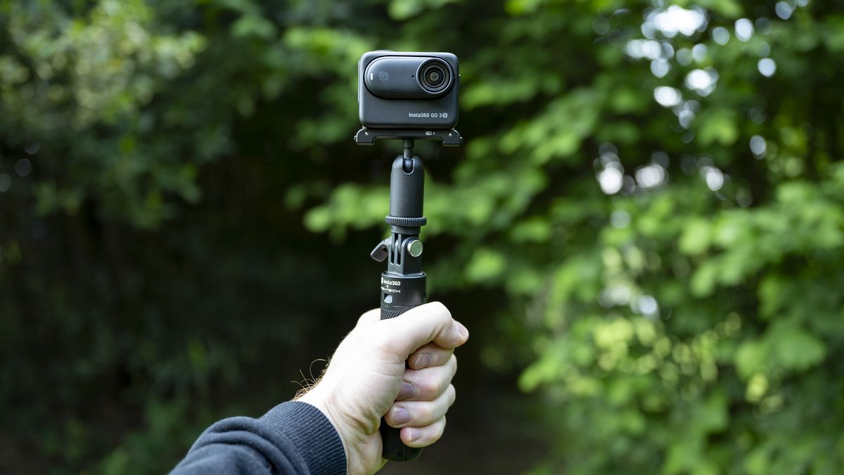 Insta360 Go 3S camera in its housing attached to a selfie stick, outdoors