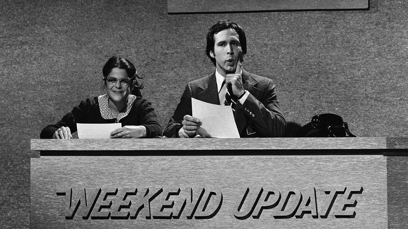 Chevy Chase and Gilda Radner sit on the Weekend Update Desk on Saturday Night Live in black-and-white NBC photo. 