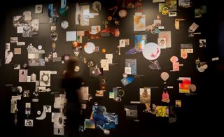 A black "Inspiration wall" filled with cutouts of different ideas from the artist.