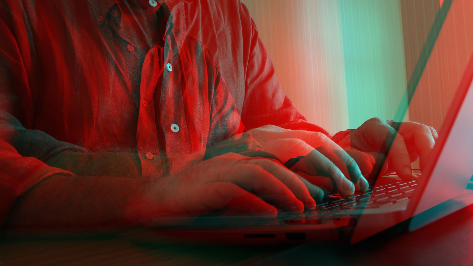 Conceptual image showing a man typing on a laptop with a vivid red-cyan glitch effect, symbolizing themes of digital overload, cybersecurity threats