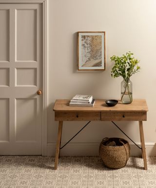 A small entryway with a gray wall, a wooden console table with decor on it, and tiled flooring
