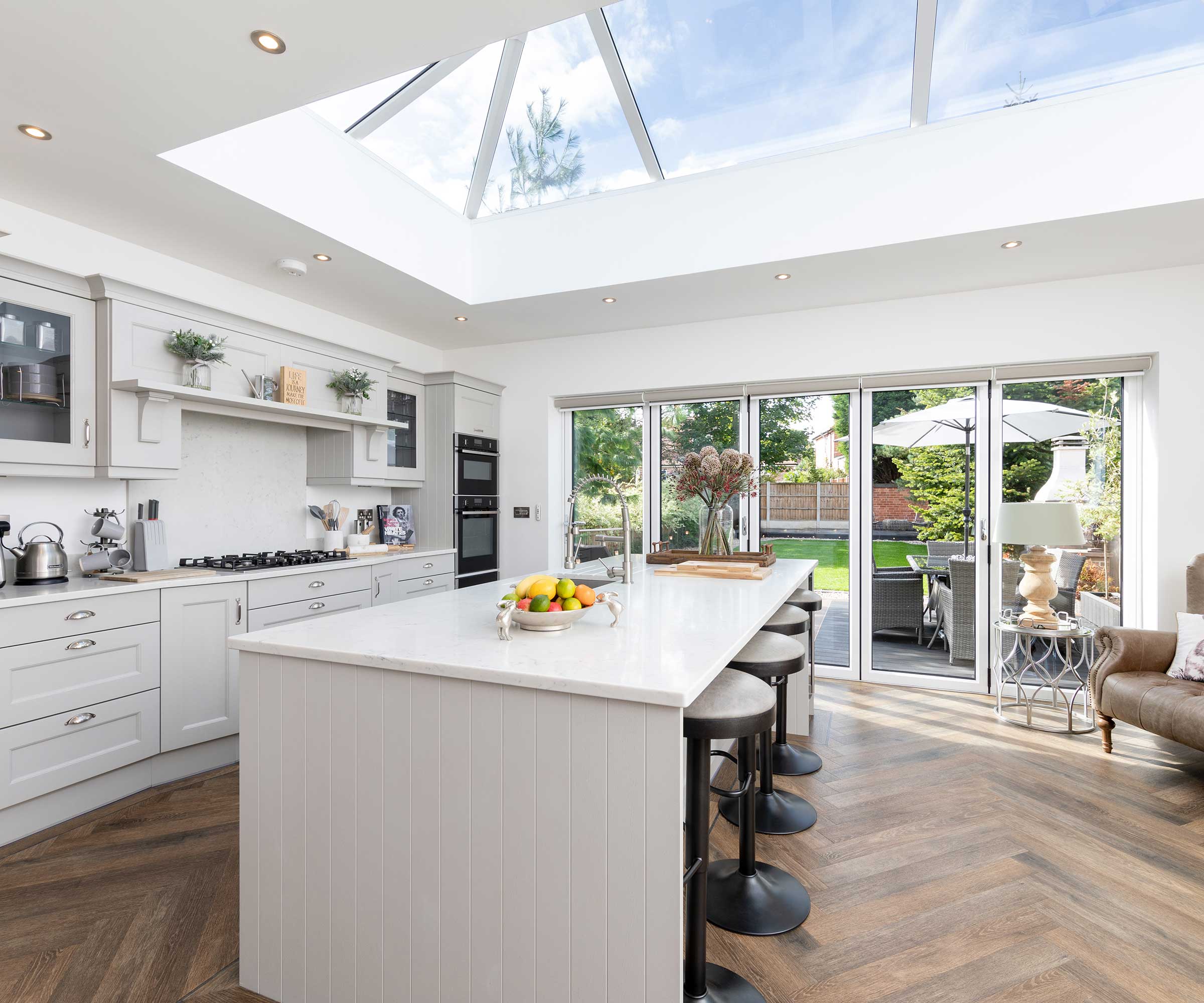 rear single-storey kitchen extension with a large roof lantern, bifold doors and a contemporary white kitchen with an island unit