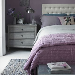 bedroom with purple wall bed with designed cushion and wooden drawer
