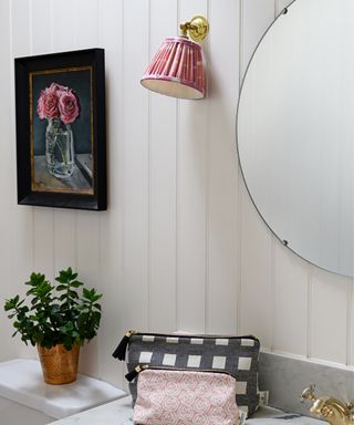 A pink pleated lampshade above a sink in a bathroom