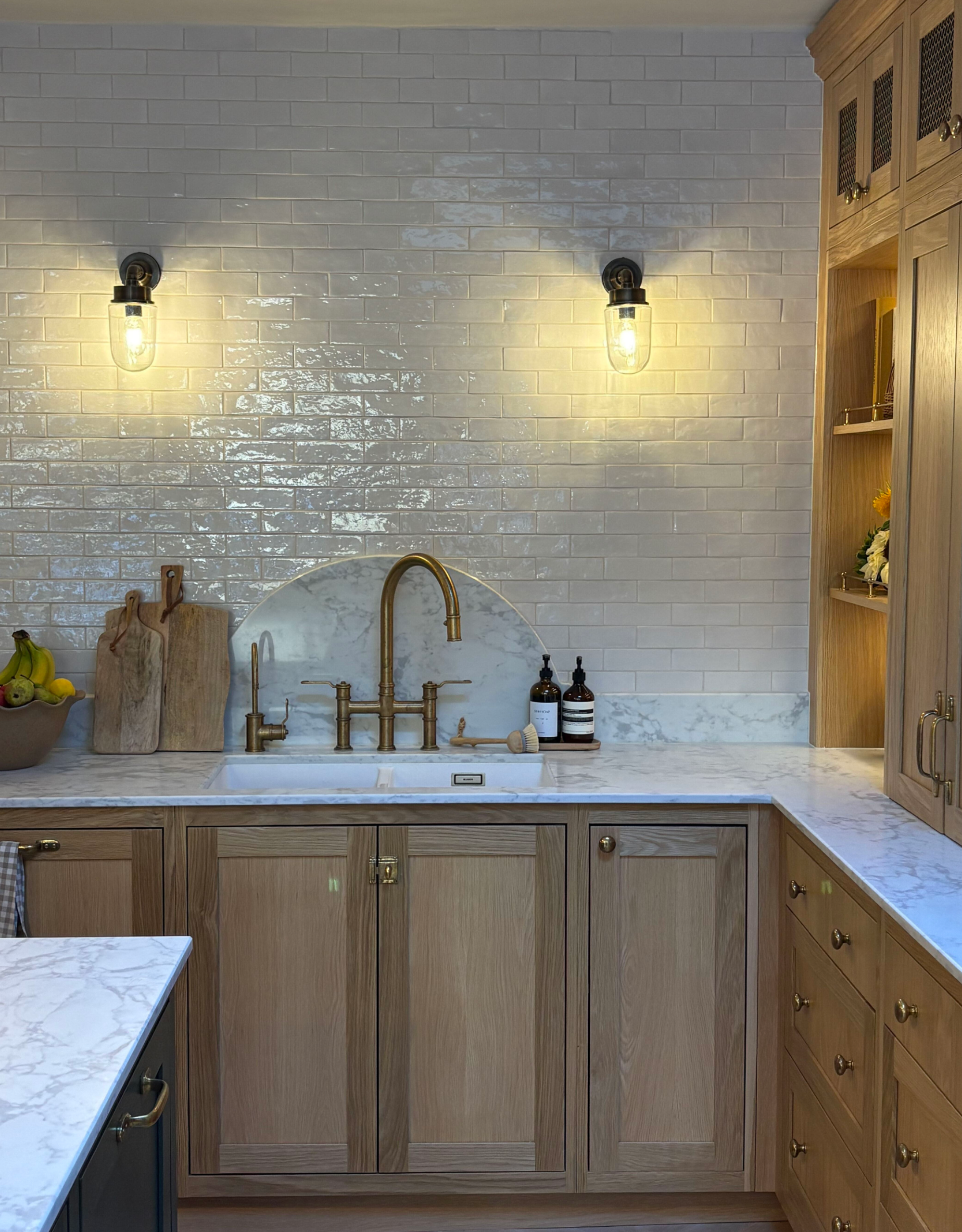 beautiful sink area with arched marble backsplash and wooden cabinetry