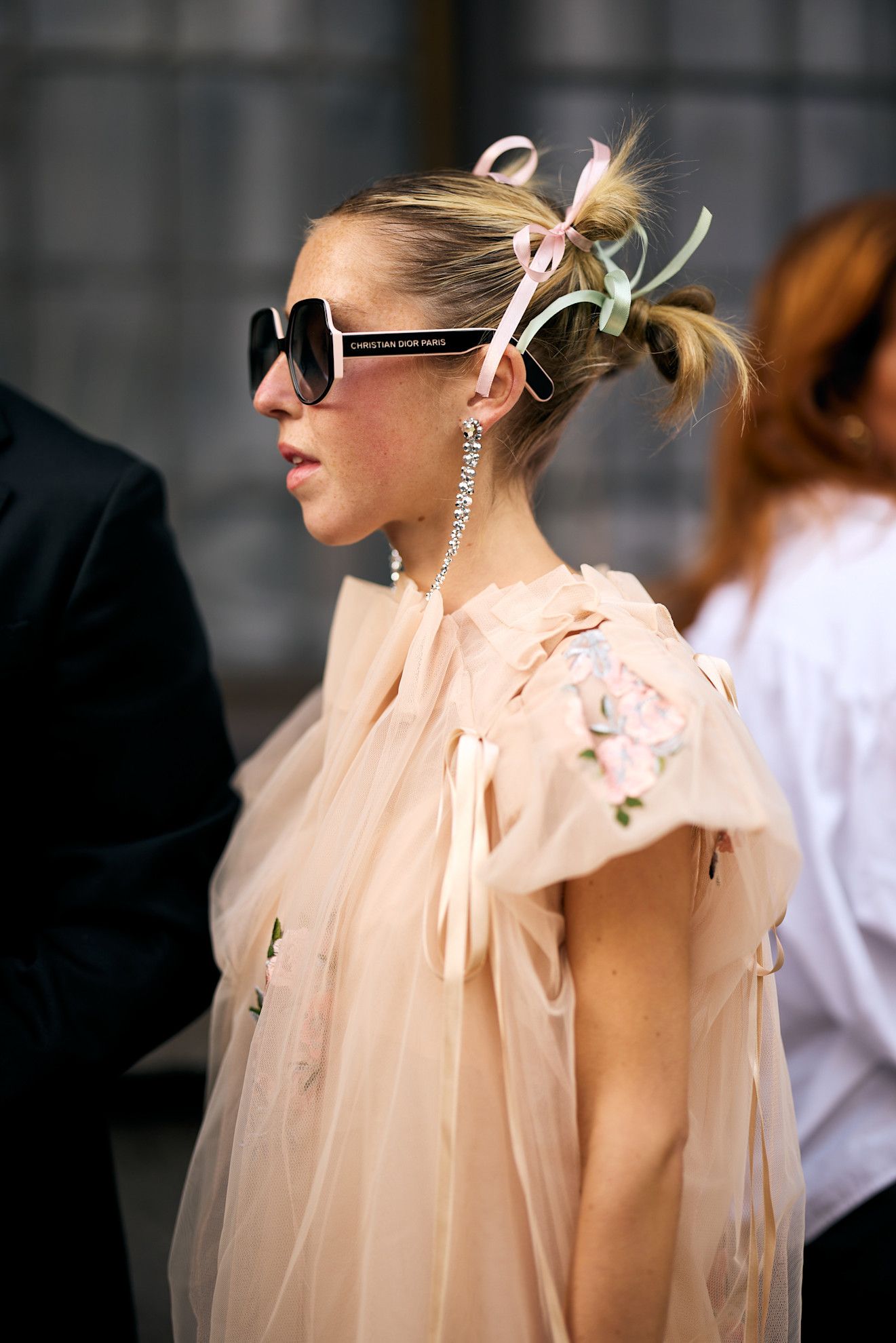 a white woman with blonde hair in a pink top with sunglasses and bows in her hair