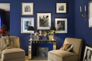 A living room with royal blue walls and pictures hanging on the walls