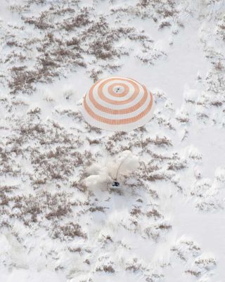 As the Soyuz spacecraft lands on the snow covered steppes in Kazakhstan a large plume of snow is displaced. The Russian spacecraft contains a NASA astronaut and Russian cosmonaut returning from the International Space Station.