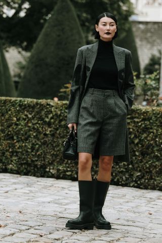 woman wearing black knee-high boots at Paris fashion week.