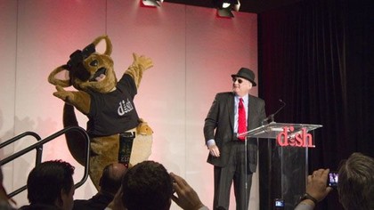 Dish CEO Joseph Clayton dances with the company mascot