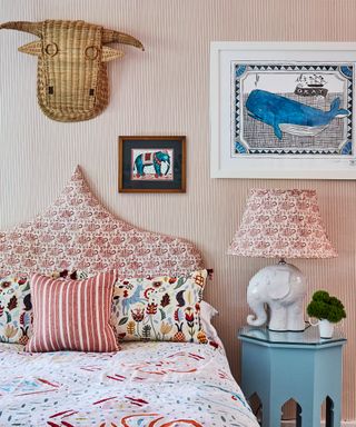 Wall decor for bedroom illustrated by a fine striped wallpaper, red patterned headboard and colorful soft furnishings and accessories.