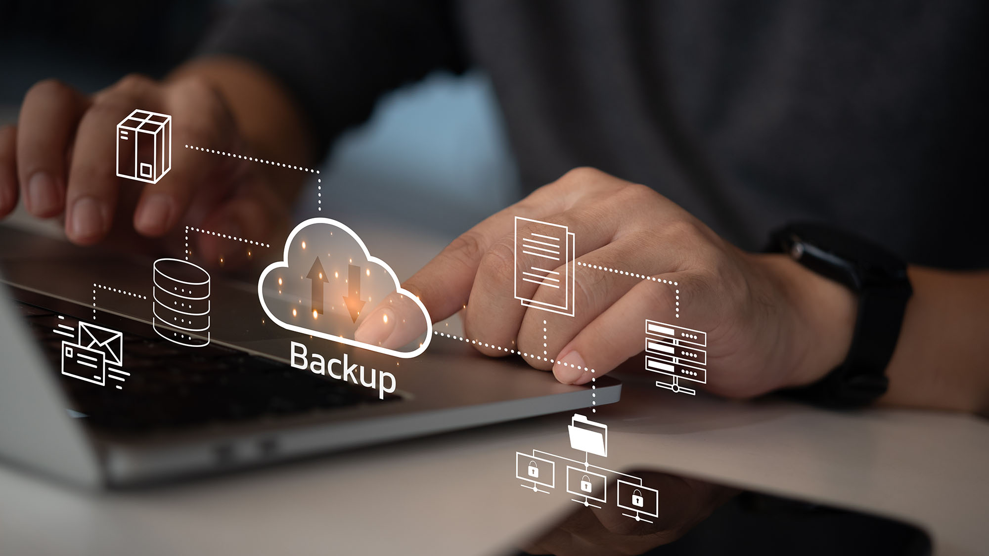 A man's hands working on a laptop with an overlaid graphic of a cloud with 'backup' written underneath and arrows representing upload and download within. Linking to the cloud are symbols for email, network storage, servers, and files.