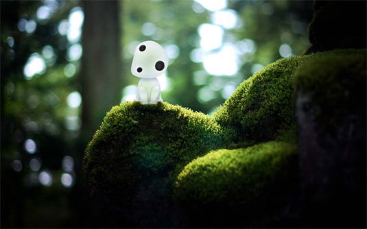 The forest spirit from Princess Mononoke sitting on mossy rocks