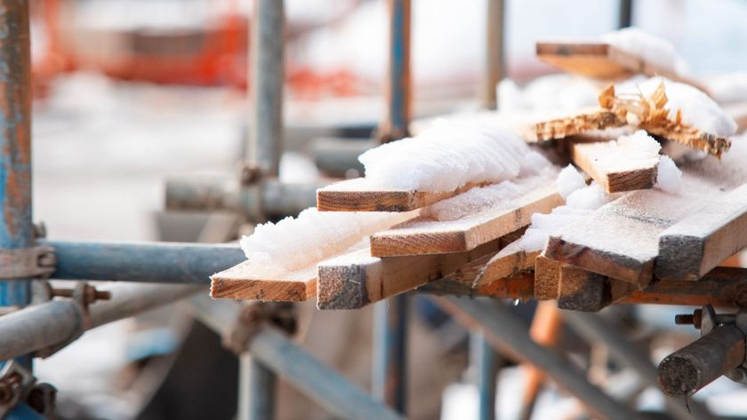 Scaffolding structure supporting construction project with intricate pipe connections and clear blue sky in background in winter