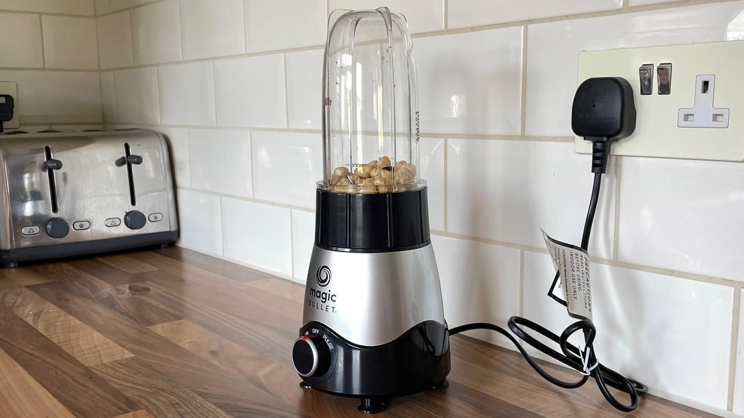 Nutribullet Magic Bullet Kitchen Express on a kitchen countertop filled with nuts ready to blend