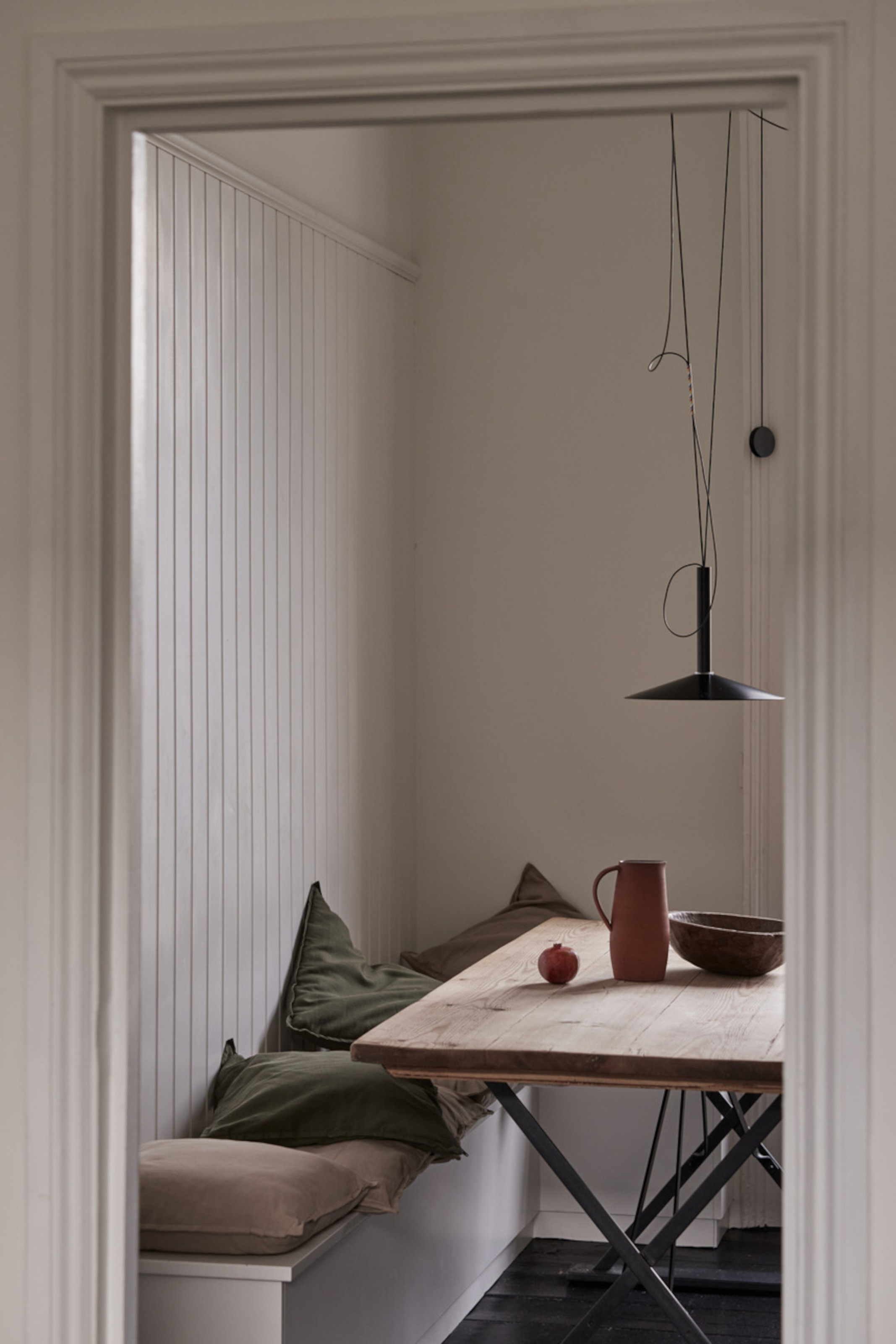 Bench seating against a wall with a fold-away dining table and a lever-operated pendant light