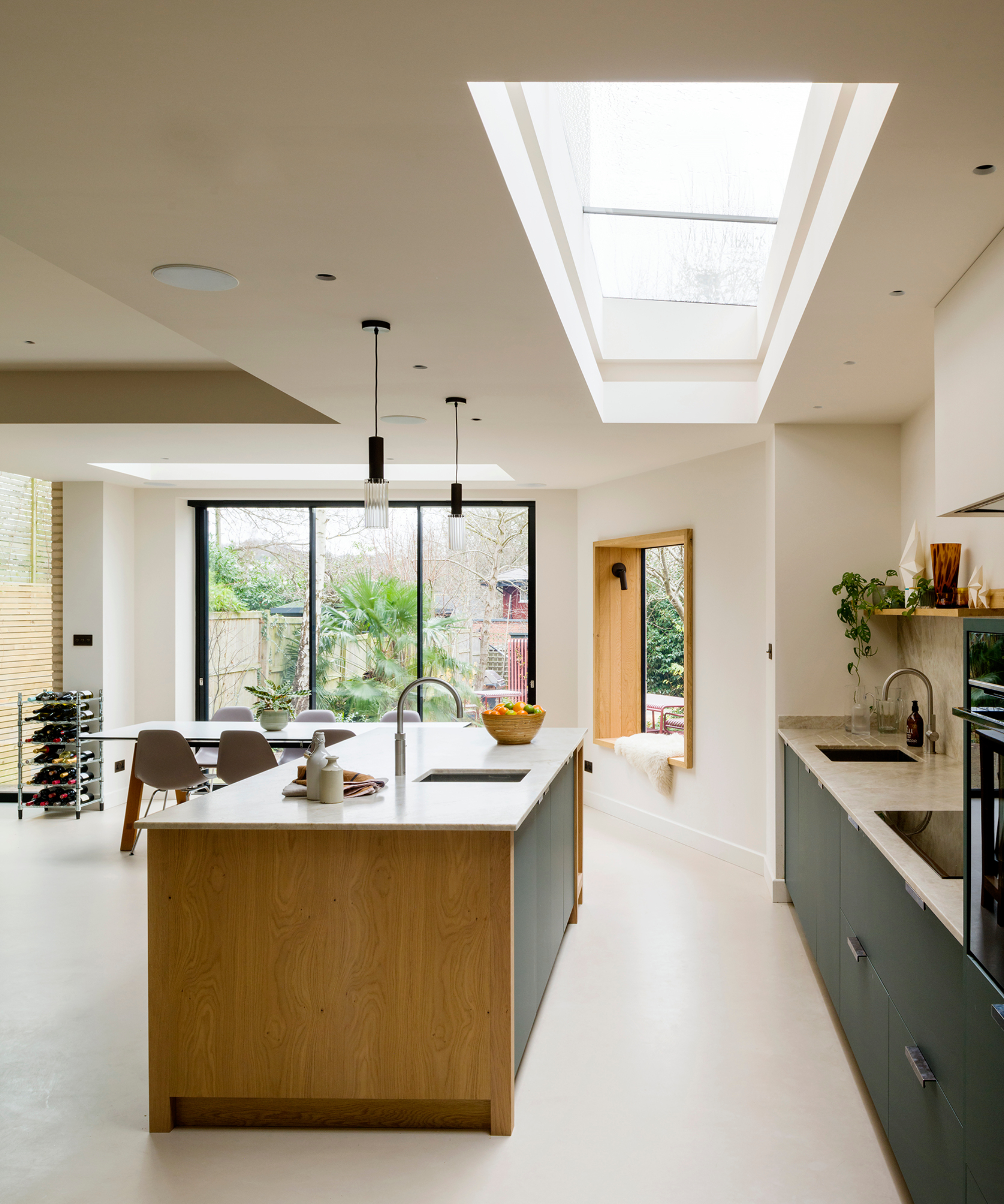 kitchen with large rooflight above space between kitchen island and back wall with units, sink and hob, pendants above island