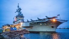 A picture taken on February 25, 2026, shows the colors of the tricolor illuminating the tower with the bridge on the French aircraft carrier Charles De Gaulle (R91) during a media tour while moored at the quay of the North Port in Malmo, Sweden. (Photo by Johan NILSSON / TT NEWS AGENCY / AFP via Getty Images) / Sweden OUT