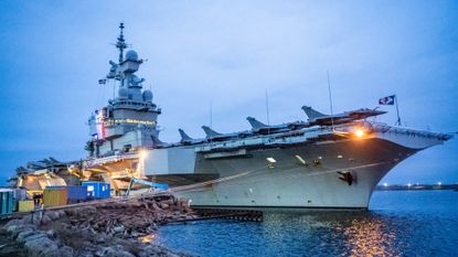 A picture taken on February 25, 2026, shows the colors of the tricolor illuminating the tower with the bridge on the French aircraft carrier Charles De Gaulle (R91) during a media tour while moored at the quay of the North Port in Malmo, Sweden. (Photo by Johan NILSSON / TT NEWS AGENCY / AFP via Getty Images) / Sweden OUT