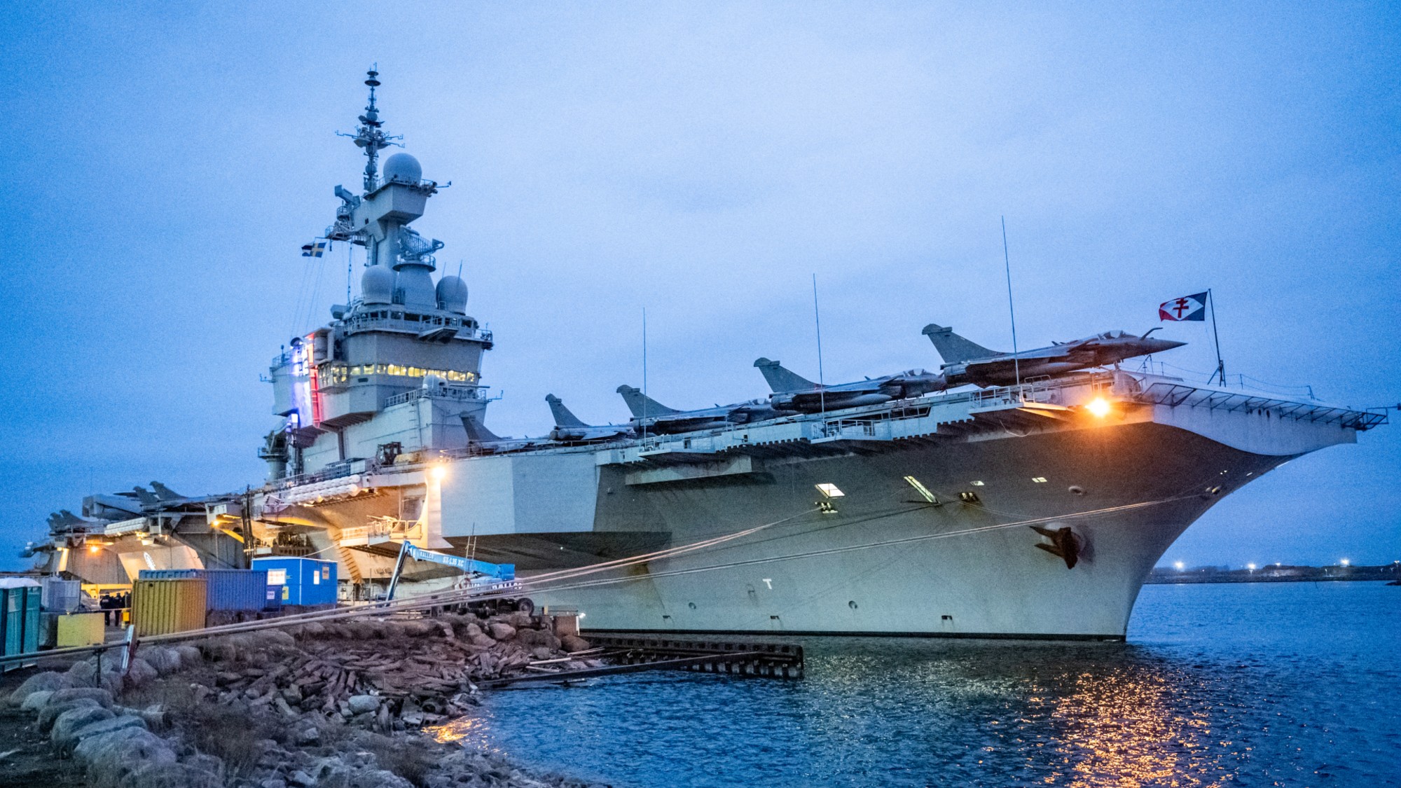 A picture taken on February 25, 2026, shows the colors of the tricolor illuminating the tower with the bridge on the French aircraft carrier Charles De Gaulle (R91) during a media tour while moored at the quay of the North Port in Malmo, Sweden. (Photo by Johan NILSSON / TT NEWS AGENCY / AFP via Getty Images) / Sweden OUT