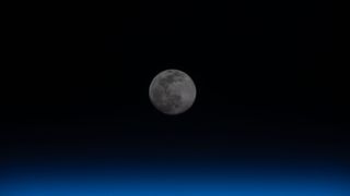 A full moon is pictured above the Earth's horizon.