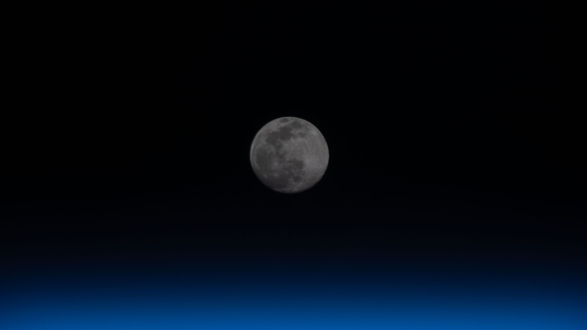 A full moon is pictured above the Earth's horizon.