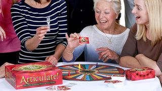 A group of people stand around an older woman playing Articulate