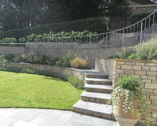 sloping garden with stone retaining walls and modern metal railings