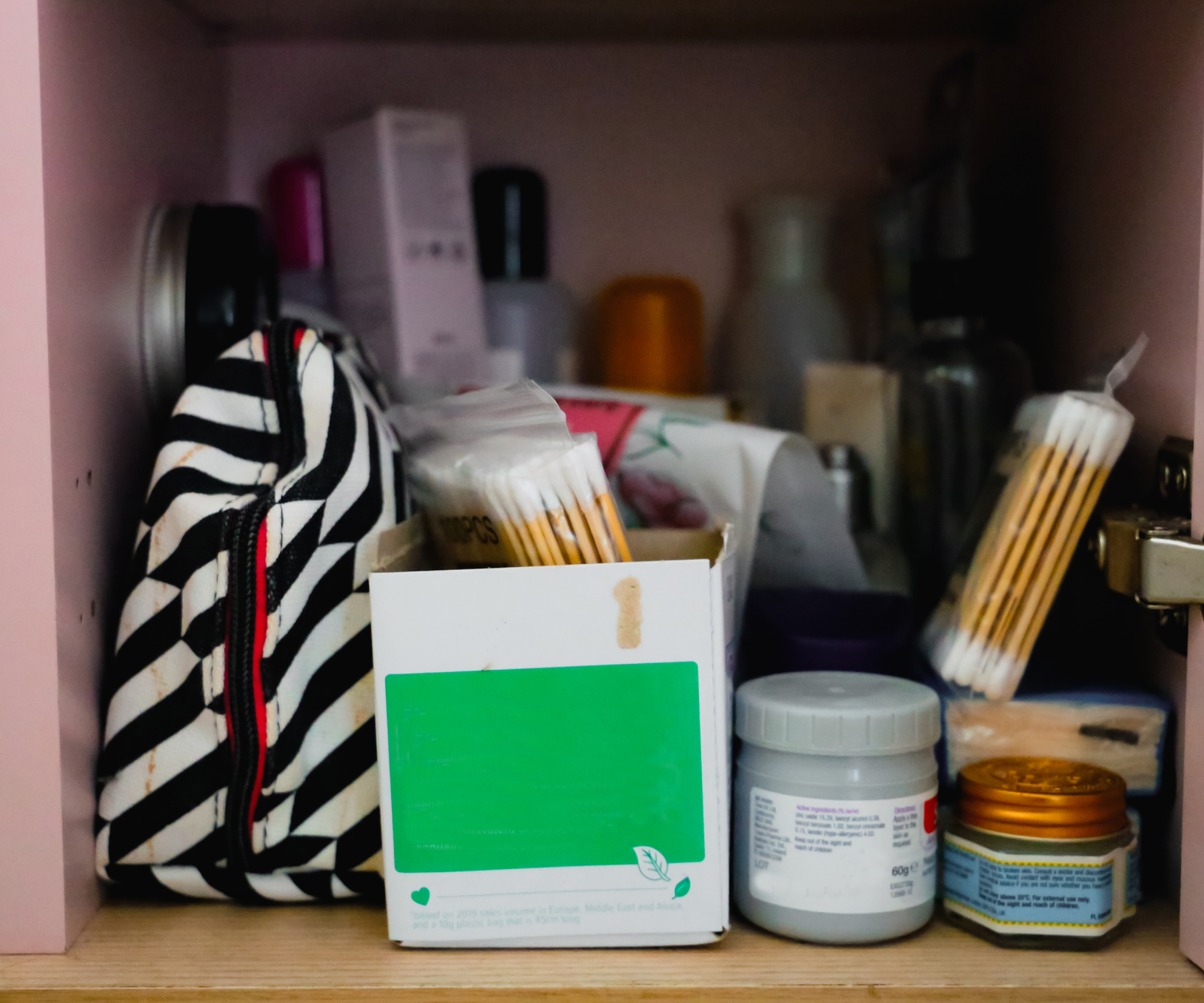 inside of bathroom cabinet with make up bag and lots of toiletries