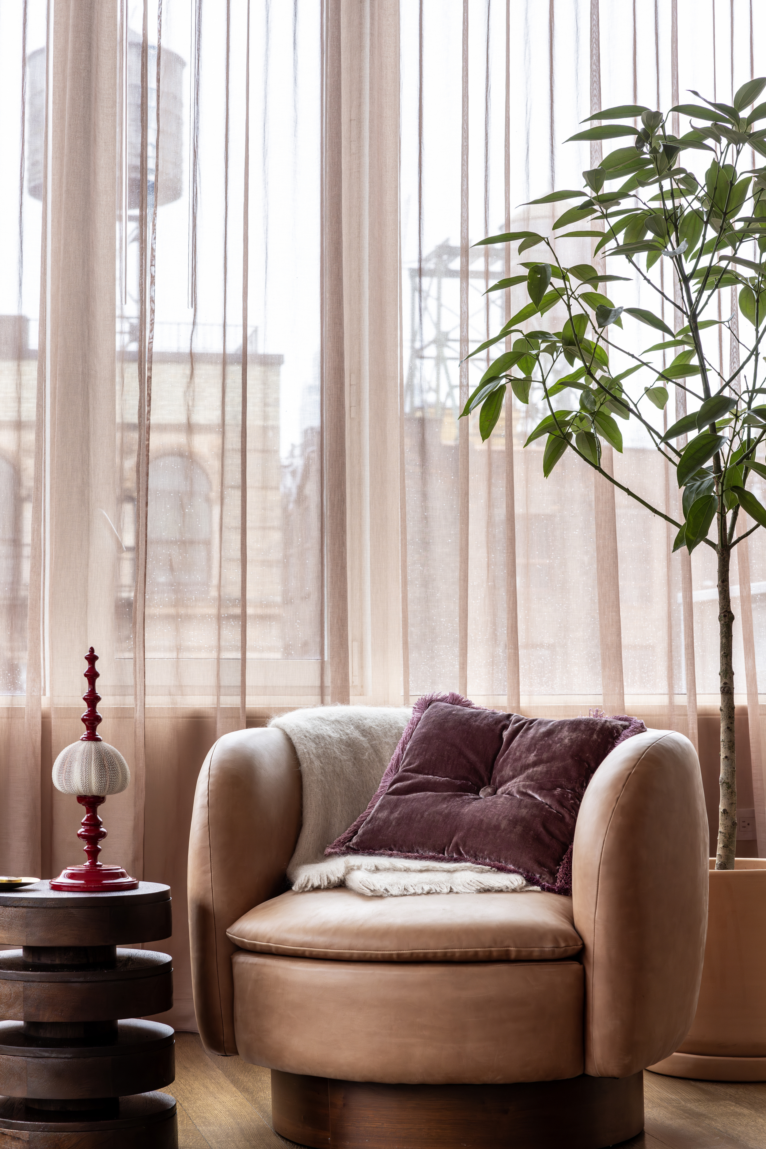 A pink colored armchair next to pink curtains