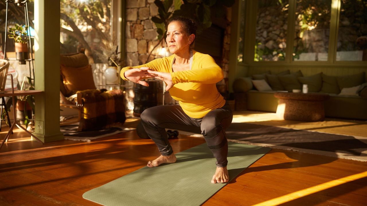 A woman performing a squat during a strength training workout at home 