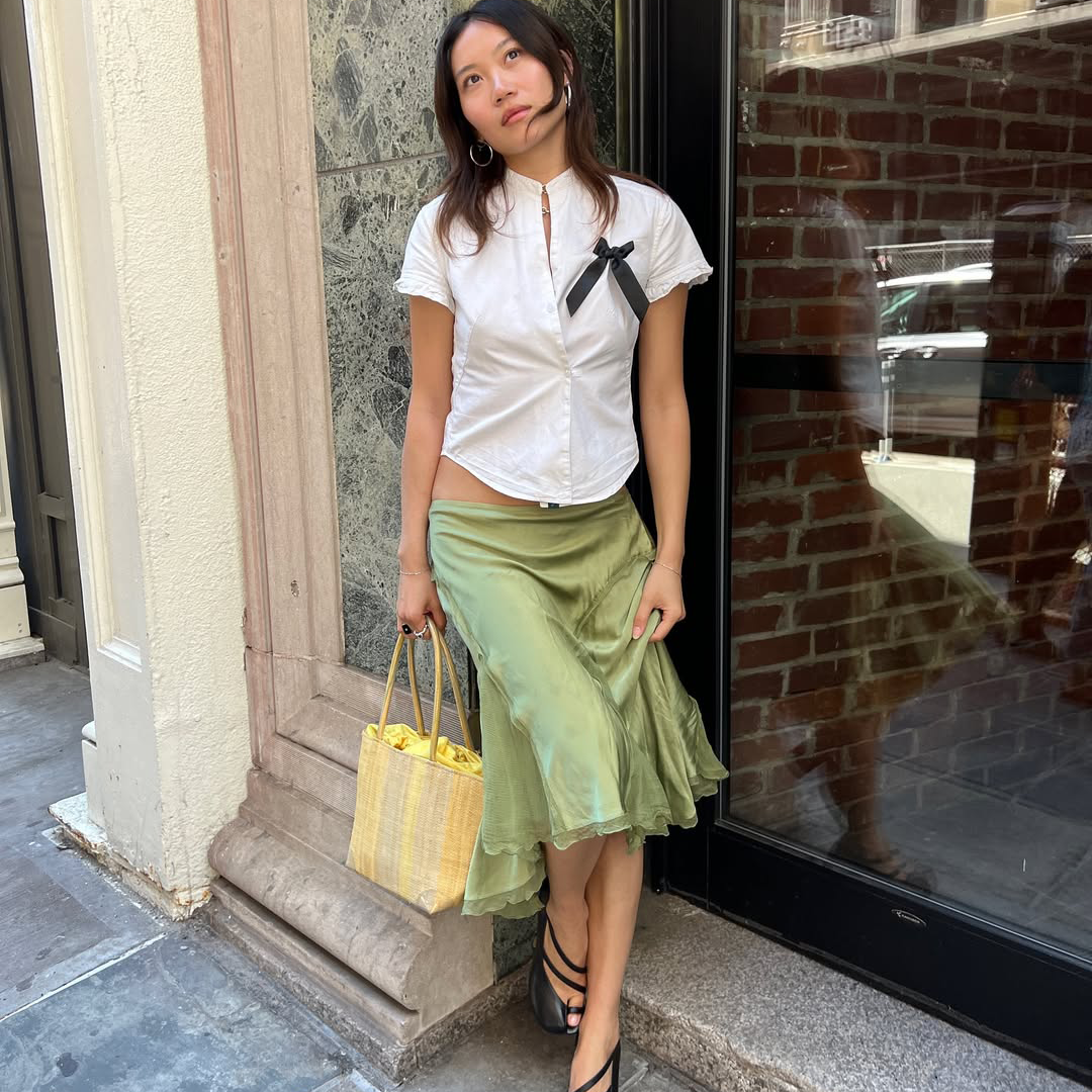A woman wearing a white top and green skirt. 