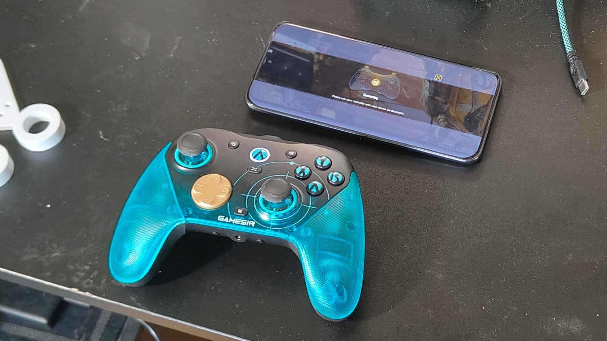 The GameSir G7 Pro 8k on a black desk, by a phone playing Call of Duty Mobile.